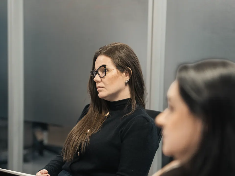 Nathália Gomes em uma sala de reunião, conversando com uma colega.